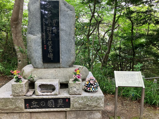 高尾山にあるシベリア抑留者供養碑。碑には「望郷 シベリアに眠る抑留者供養碑」と刻まれている。また、隣に「嗚呼シベリア鎮魂歌(レクイエム)」という歌の歌詞のパネルが置かれている。碑に置かれた花は造花。