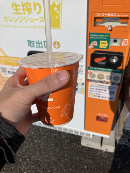 自販機の前で購入したオレンジジュースを撮影