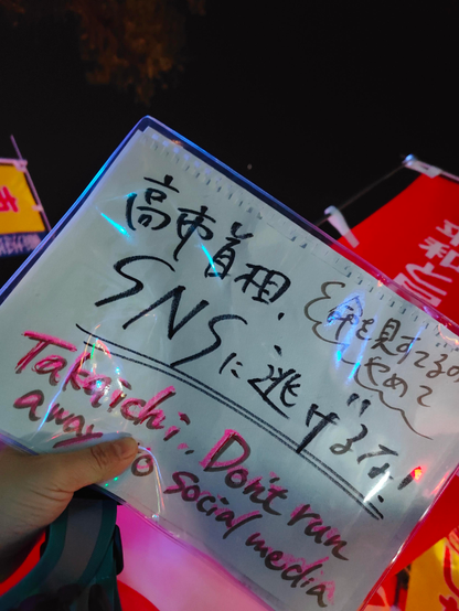 手書きのプラカードの写真。「高市首相、SNSに逃げるな。命を見捨てるのやめて」と書いてある。